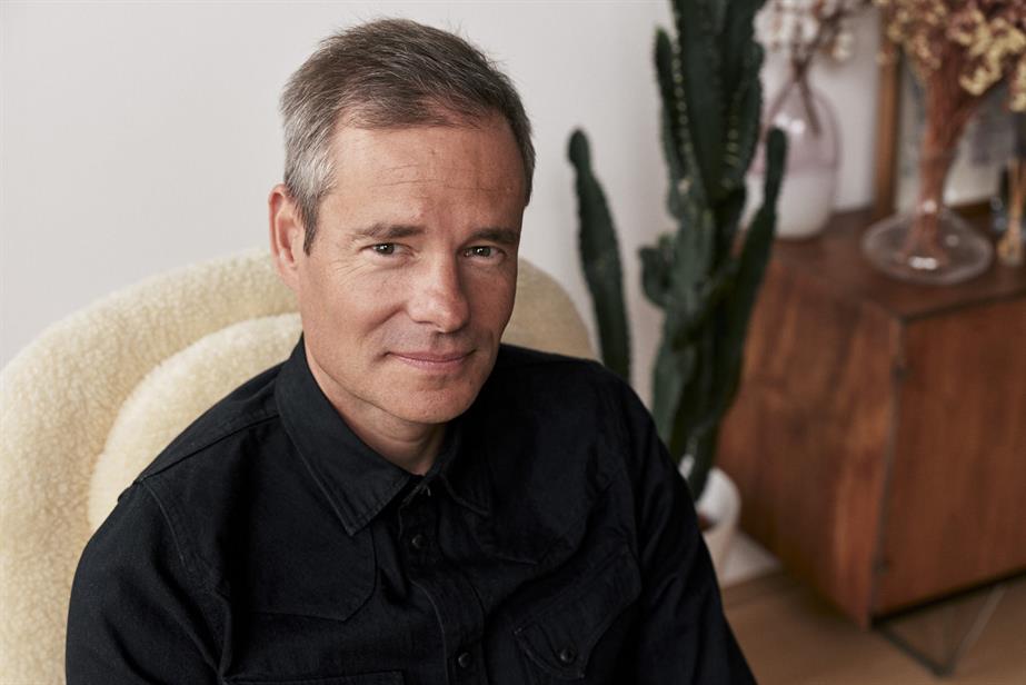 Photo of Alex Grieve on a cream chair in front of a side board