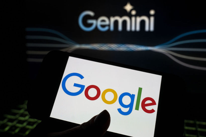 Smart phone displaying Google logo with Gemini ad in the back