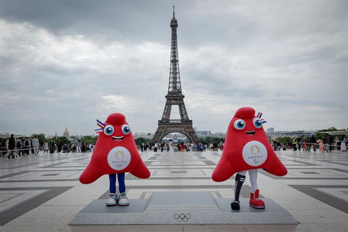 The Paris Olympics and Paralympics mascots stand in front of the Eiffel Tower