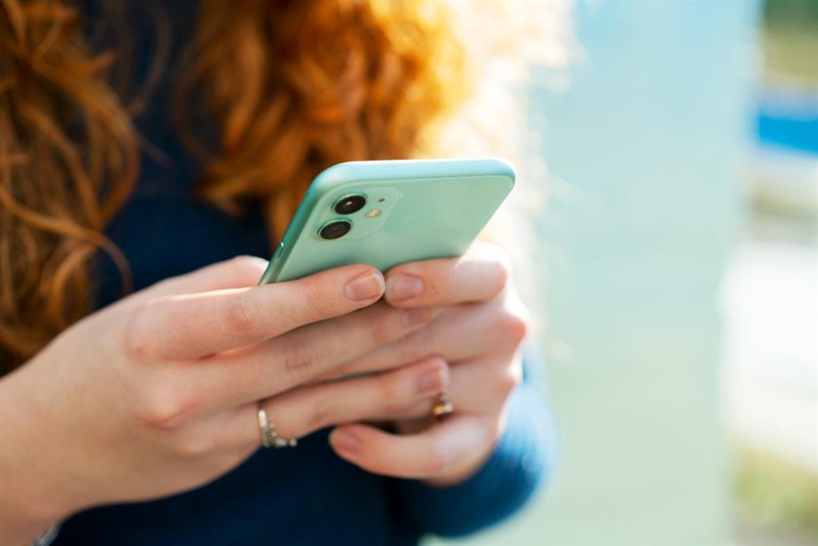 A girl scrolls on her phone.